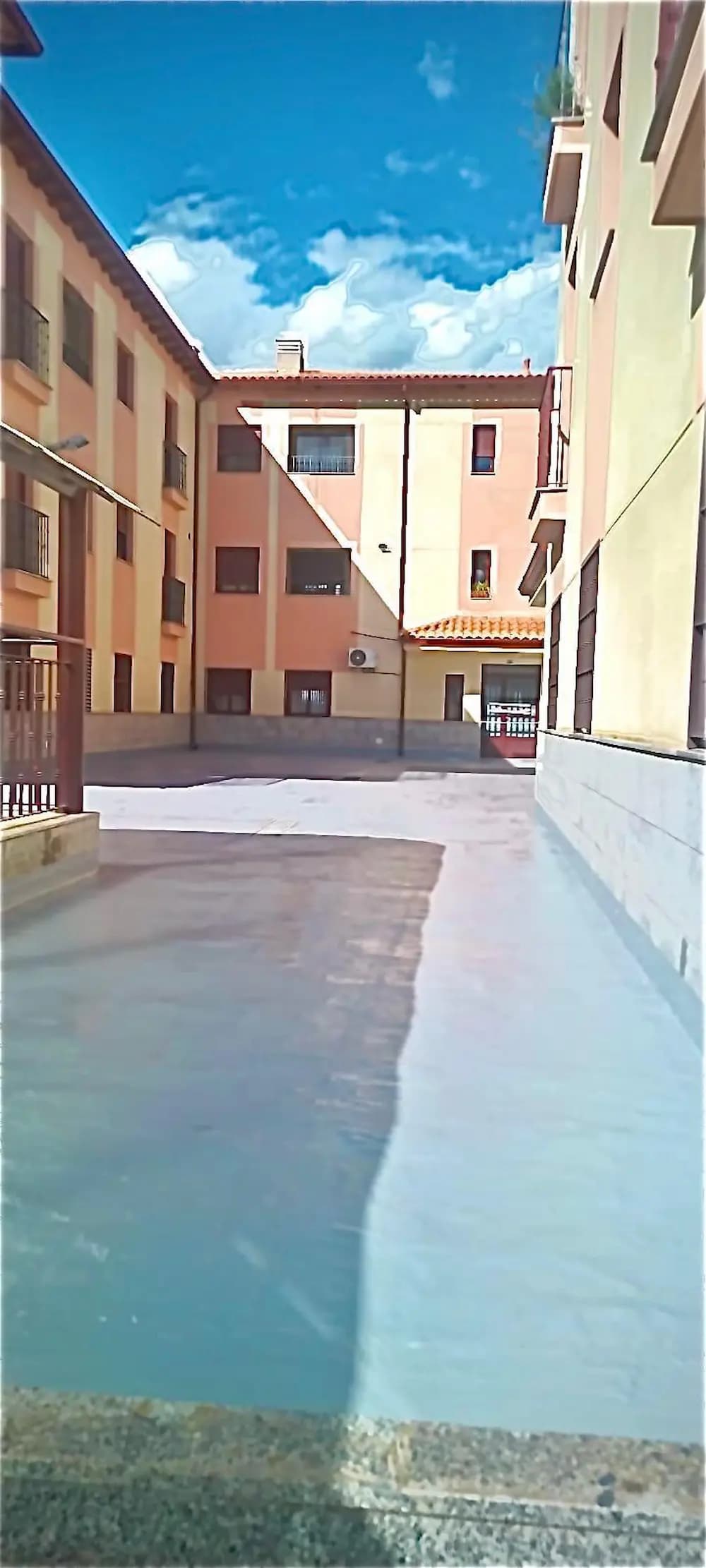 Zona de paso entre edificios de viviendas con el suelo impermeabilizado en gris claro